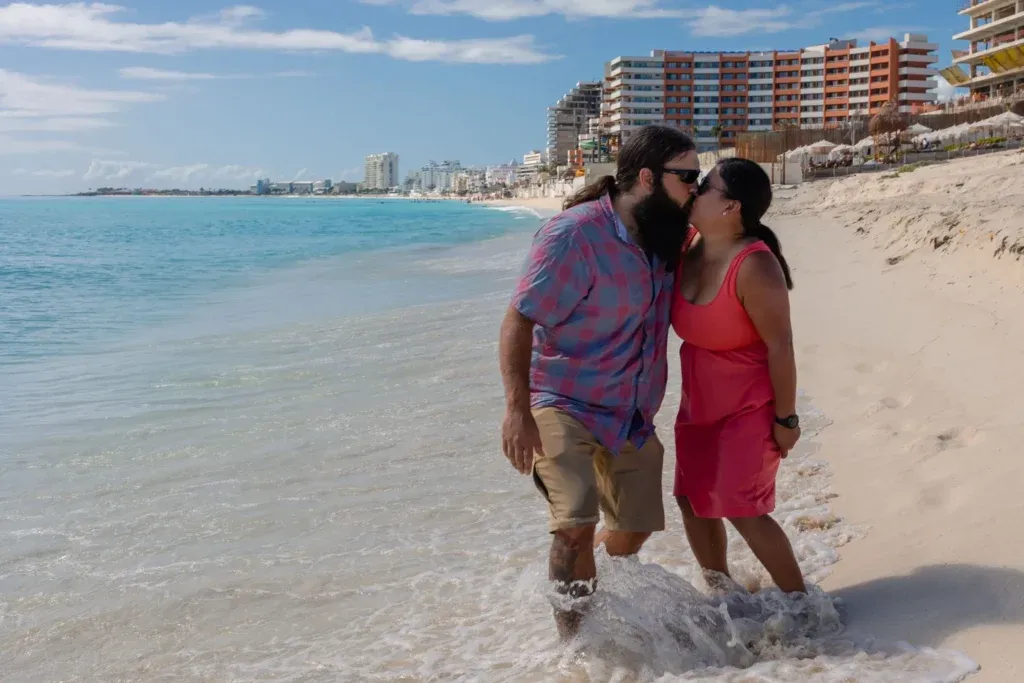 A young Canadian couple and their baby posing for a family photo session at Playa Delfines beach in Cancun, Mexico.