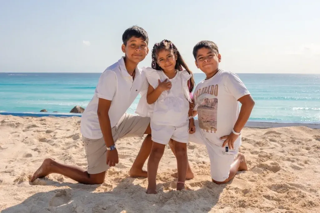 Family with parents and three children enjoying a beach photography session at Playa Delfines in Cancun.