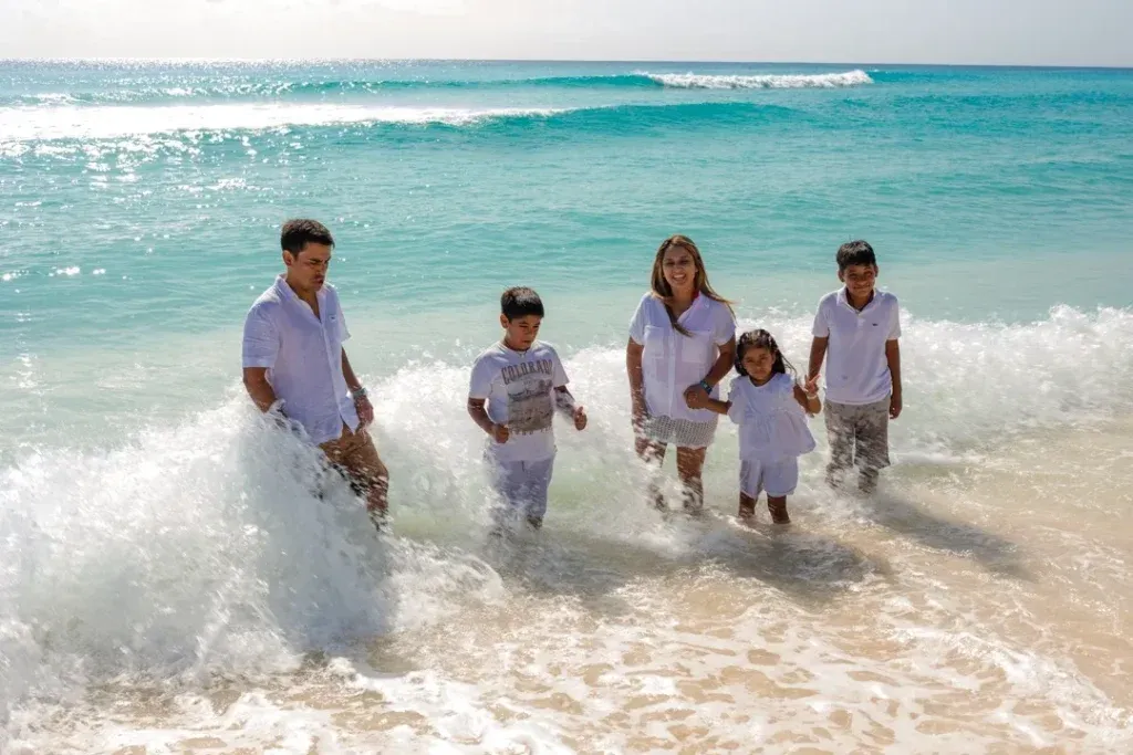 Family with parents and three children enjoying a beach photography session at Playa Delfines in Cancun.
