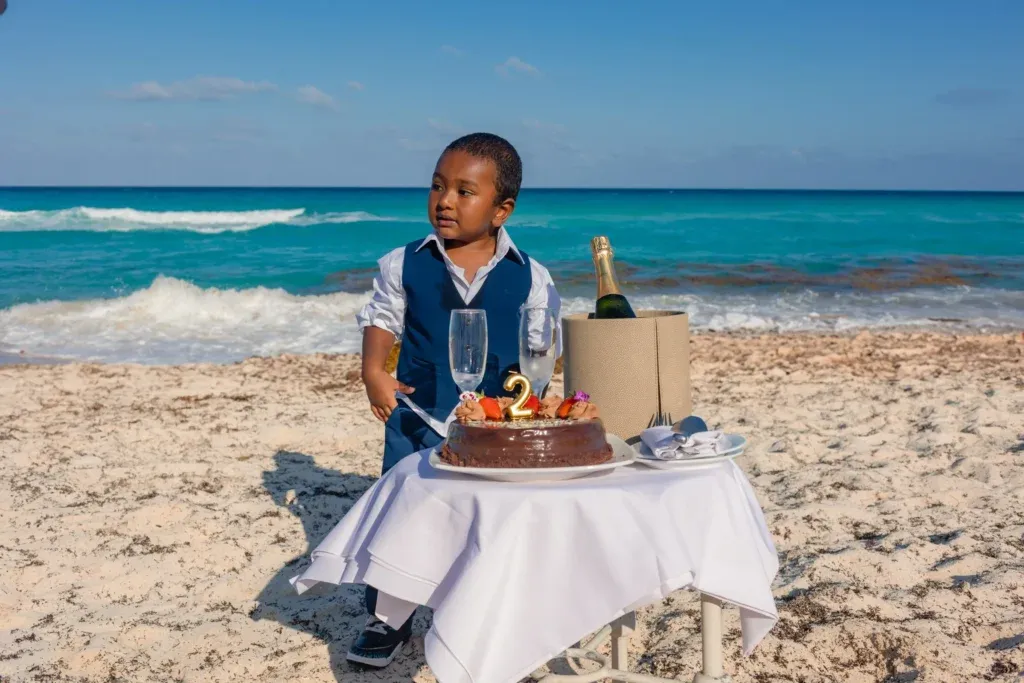 Family celebrating a two-year-old birthday on a Cancun beach with cake smash photos and romantic couple portraits by the Caribbean Sea.