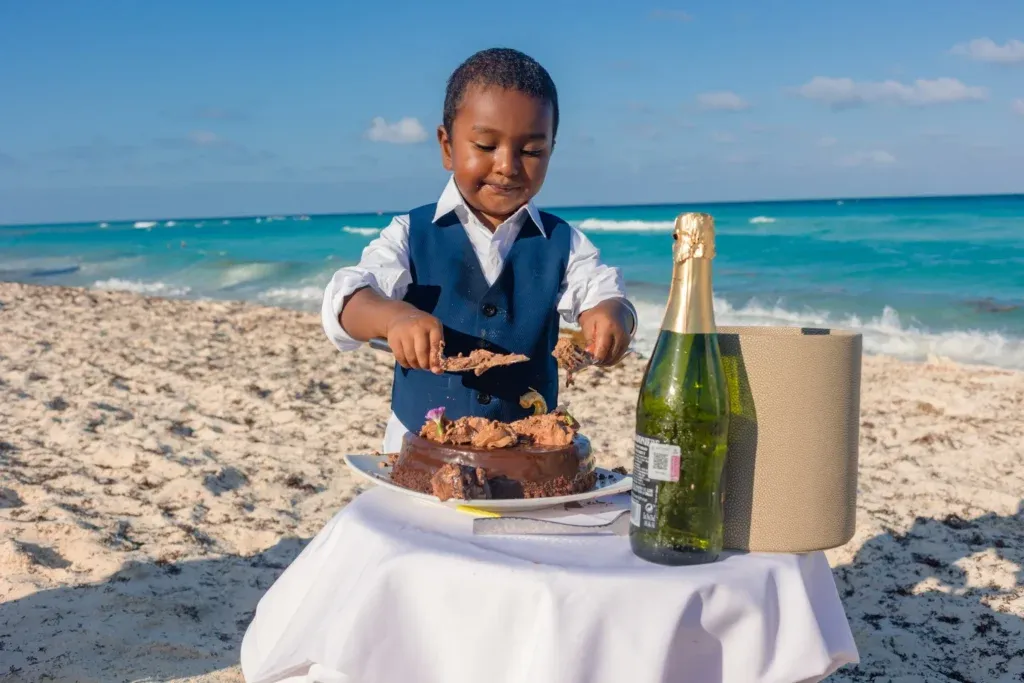 Cancun family photographer captures a two-year-old birthday cake smash on the beach with family portraits and Caribbean Sea views.