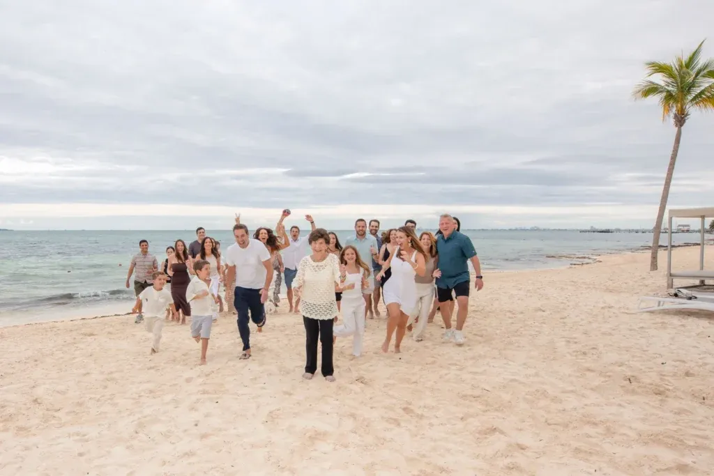Large family celebrating a grandmother’s 90th birthday at Garza Blanca Resort & Spa Cancun with portraits in the lobby, pool area, and beach.
