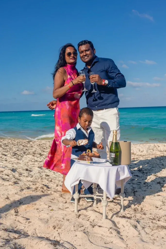 Family celebrating a two-year-old birthday on a Cancun beach with cake smash photos and romantic couple portraits by the Caribbean Sea.